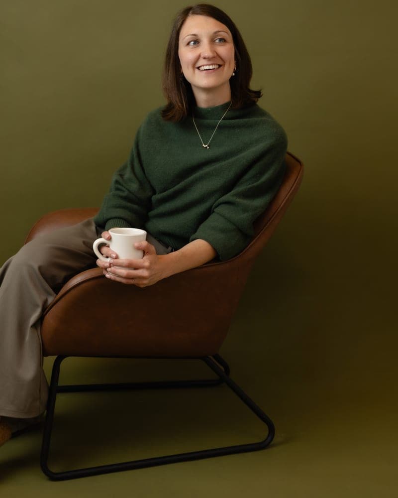 Marni seated in a chair holding a mug